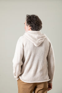 Gray haired bohemian man facing backwards wearing a white alpaca hoodie for men and tan khaki pants. 