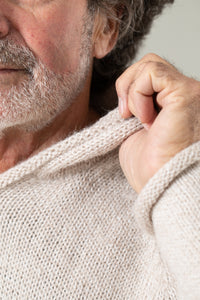 Detailed neck image of an alpaca hoodie on a man with a white beard and gray hair. 